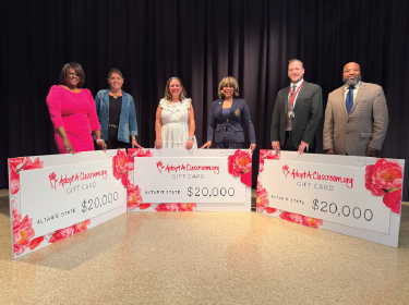 teachers standing with large checks